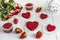 Red cake without cream `red velvet` on a white wooden table, decorated with strawberries, roses and white openwork vase with a hea