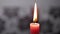 Red Candle Burning with a Bright Flame on a Gray Floral Blurred Background