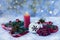A red candle, Christmas tree toys, Christmas tree branches, rowan, cones on a snowy window background.