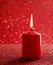 Red candle. Red glittering christmas lights. Blurred abstract ba