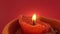 Red candle with yellow flame lit and blown out with smoke against red background in slow motion