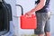 Red canister in the hands of a man. Filling a stalled car with gasoline from a canister