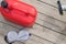 Red canisters with fuel for filling chainsaws, on a wooden background, with eye protection items