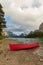 Red canoe on rocky beach surrounded by mountains