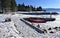 A red canoe sleeping on the snowy beach of Lake Tahoe