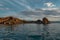 Red cape Shamanka in clear blue Lake Baikal among the rocks, mountains and clouds, sunset