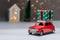 A red car on the background of a forest and a house will bring Christmas New Year gifts