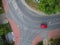 Red car driving across curved intersection in city, aerial view