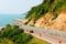 Red car driving on the beautiful curve road beside sea view and mountain on vacation day at Viewpoint Nang Phaya, Chanthaburi, Tha