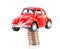 Red car model jacked by a stack of dollar coins on white background