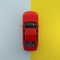 Red car on pastel blue and yellow contrast background. top view. minimal concept