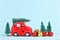 Red car transporting christmas tree snowballs and gift boxes