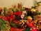 Red cardinal sitting among Christmas evergreens, pine cones, poinsettas, red berries