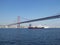 A red cargo ship crosses a liner under the bridge of April 25 in Lisbon, Portugal, Europe