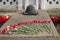 Red carnation flowers flowers lie on a tombstone with a bronze helmet during the celebration of Victory Day WWII.