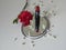 Red carnation, red lipstick, white gypsophila flowers and mirror