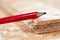 Red carpenter pencil resting on a piece of chip board. Blurred background