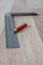 Red Carpenter`s Pencil and Right Angle`s Tool on Laminate Floor