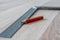 Red Carpenter`s Pencil and Right Angle`s Tool on Laminate Floor