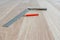 Red Carpenter`s Pencil and Right Angle`s Tool on Laminate Floor