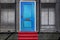 Red carpet leading to a blue door in a metal security fence