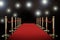 Red carpet and rope barrier with shining spotlights