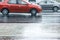 Red cars driving on wet asphalt road during rainy weather