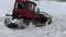 The red caterpillar tractor removes snow from the road.