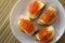 Red caviar on bread and butter closeup, four sandwiches on white plate. View from above