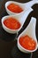 Red caviar in small bowls on black glass background. top view.