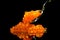 Red Caviar in a spoon. Caviar isolated on black background. Fish roe, Close-up salmon or trout caviar