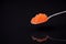 Red caviar in a spoon on a dark background with reflection below. Caviar, seafood, Shrovetide. Russian traditional food