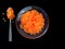 Red caviar in a transparent plate. Salmon ROE on a spoon. Delicacy on a black background. Seafood
