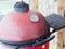 Red ceramic barbecue grill with thermometer on the lid. Closeup photo