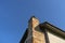 A red ceramic brick chimney standing at the rear of the building, by the facade, with a blue sky in the background.