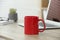 Red ceramic mug and laptop on wooden table indoors
