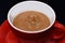 Red ceramic mug pouring, filling with coffee, sackcloth background.