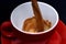 Red ceramic mug pouring, filling with coffee, sackcloth background.