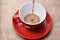 Red ceramic mug pouring, filling with coffee, sackcloth background.