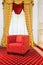 Red chair in the room with vintage red carpet and classic yellow drapes