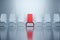 A red chair stands among white ones on a light background. The concept of uniqueness, important guest, boss, non-standard trip,