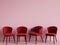 Red chairs are standing in an empty pink room.