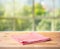 Red checked tablecloth on wood with blur green bokeh from window kitchen background.Summer and picnic concepts