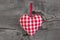 Red checkered heart shape hanging on a wooden background for val