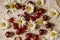 Red cherries on an openwork white paper napkin with flower heads of field daisies on a wooden table