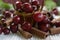 Red cherries with stems and cinnamon rods on white tablecloth