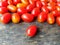 Red cherry tomato, one piece in front of, reader in business, wooden background