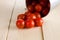 Red cherry tomatoes spilled on white wooden board