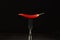 Red chili pepper on a fork lies on a black background.