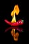 Red chilli on black surface with flames